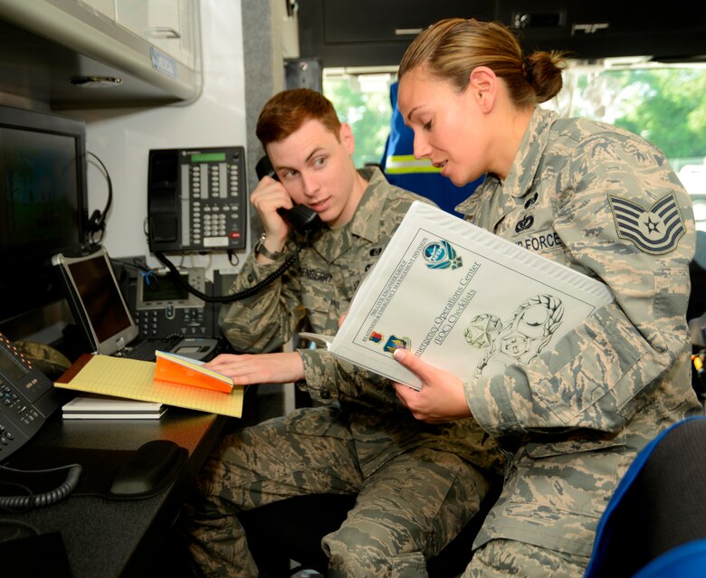 Airman 1st Class Jeffrey Quisenberry, REM technician, takes a call as he and Adams go through a series of emergency response checklists. (U.S. Air Force photo by Ed Aspera)


