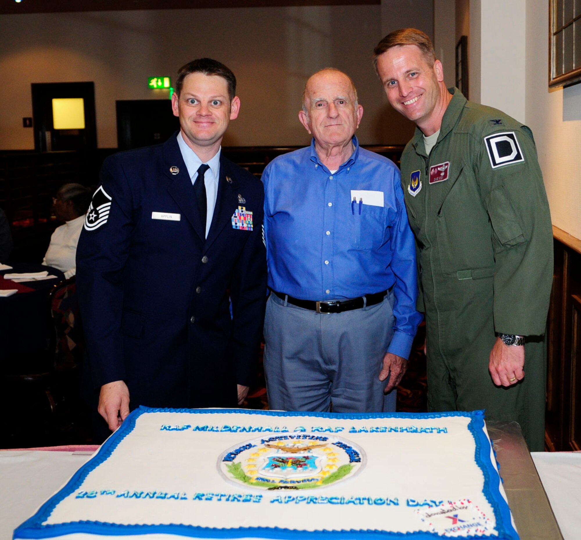 U.S. Air Force Master Sgt. Brian Applin, left, 352nd Special Operations Support Squadron group superintendent of communications and Retiree Appreciation Day committee chair; Roland Boucher, center, Retiree Affairs Office volunteer, and U.S. Air Force Col. David Cox, right, 100th Air Refueling Wing vice commander, pose next to the cake June 6, 2014, at the RAD event on RAF Mildenhall, England. Retirees living in the United Kingdom came together for a day dedicated to them and saw demonstrations and static displays. (U.S. Air Force photo/Karen Abeyasekere/Released)