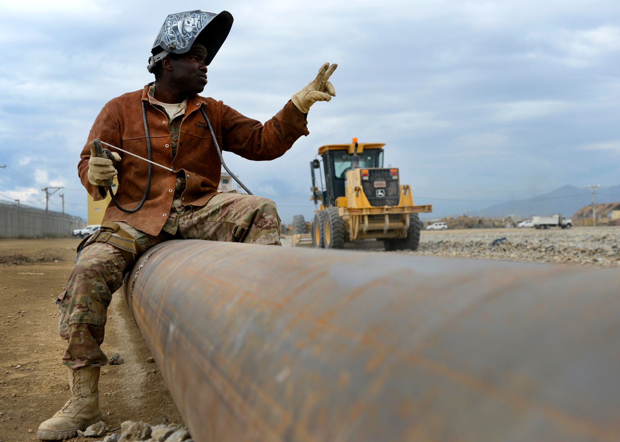 U.S. Air Force Staff Sgt. William Thomas, 577th Expeditionary Prime Base Engineer Emergency Force Squadron troop construction bravo, requests two more welding rods while welding together two drainage pipes at Bagram Air Field, Afghanistan, May 17, 2014. The drainage pipe will assist in keeping the helicopter landing zone free of water. Thomas, a Cincinnati, Ohio native is deployed from the 786th Civil Engineer Squadron Ramstein Air Base, Germany. (U.S. Air Force photo by Senior Airman Sandra Welch) 