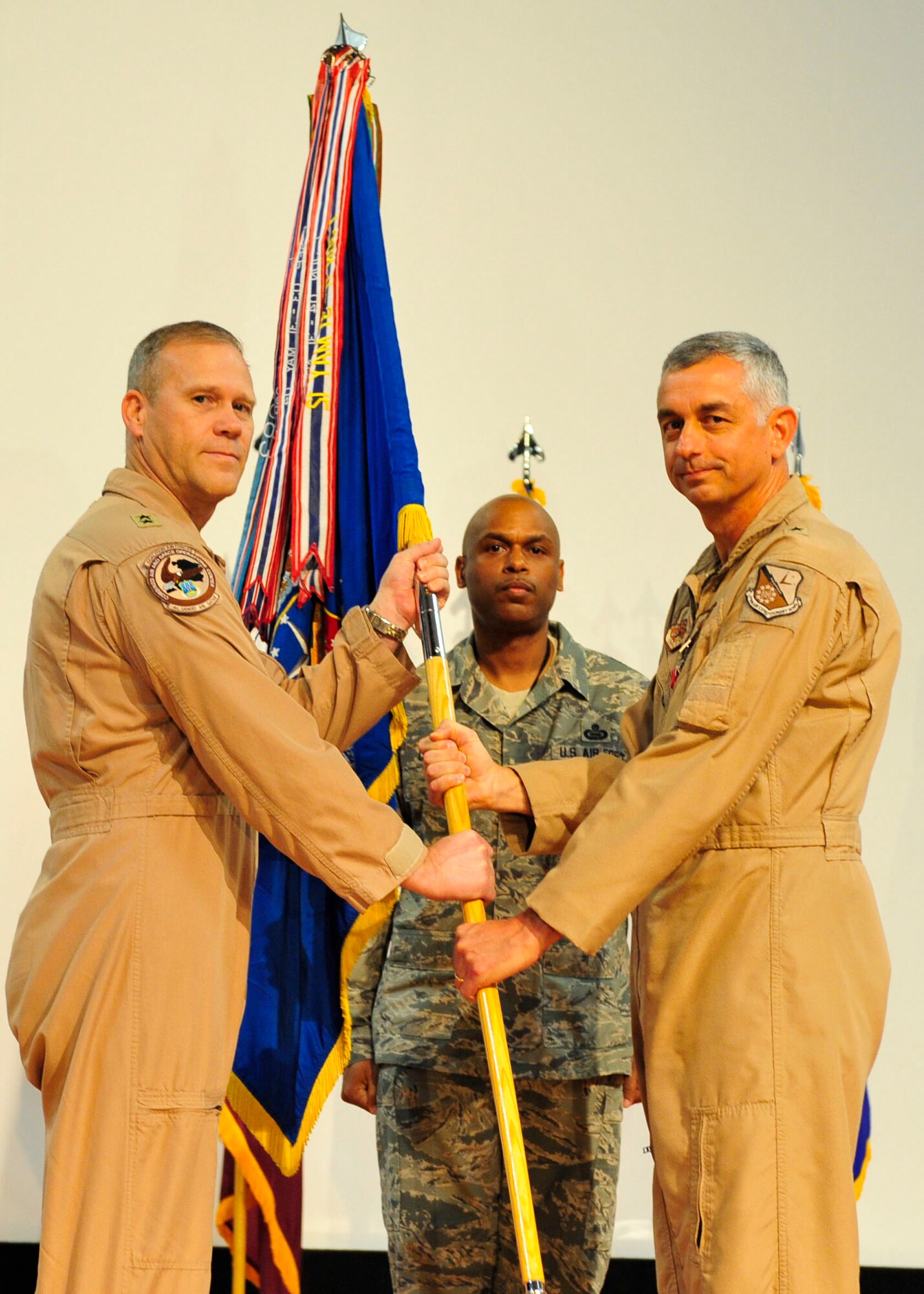 U.S. Air Force Maj. Gen. Jeffrey Lofgren of U.S. Air Force Central Command  deputy commander, takes the guidon from Brig. Gen. Roger Watkins, 379th Air Expeditionary Wing outgoing commander, during the change of command ceremony at Al Udeid Air Base, Qatar, June 12, 2014. Watkins served as the commander of the 379th AEW for two years. (U.S. Air Force photo by Senior Airman Colin Cates)