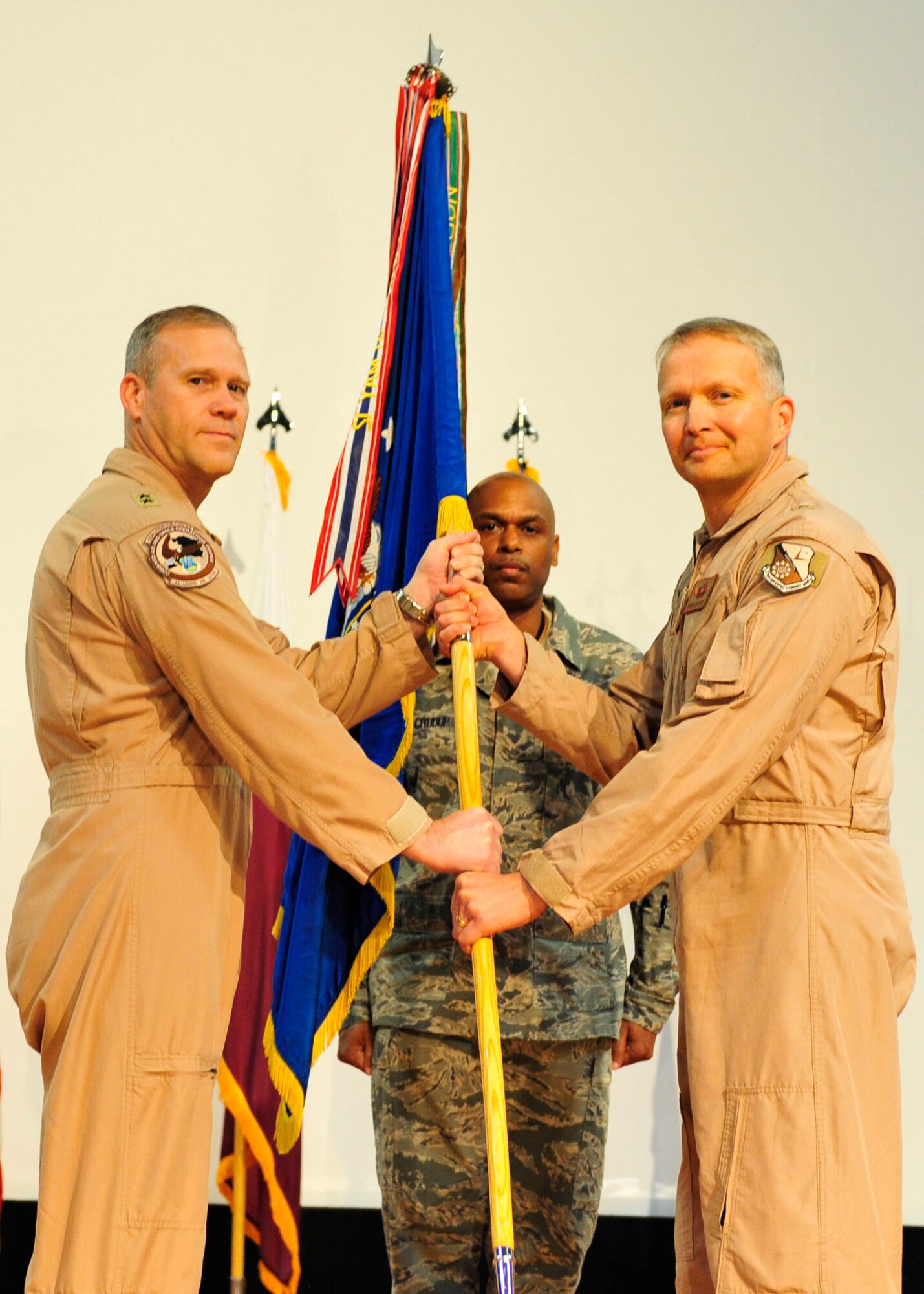U.S. Air Force Maj. Gen. Jeffrey Lofgren, deputy commander of U.S. Air Forces Central Command passes the guidon to Brig. Gen. Darren Hartford, 379th Air Expeditionary Wing commander, during the change of command ceremony at Al Udeid Air Base, Qatar, June 12, 2014. Before assuming command, Hartford served as the commander of the 437th Airlift Wing at Joint Base Charleston, South Carolina. (U.S. Air Force photo by Senior Airman Colin Cates) 