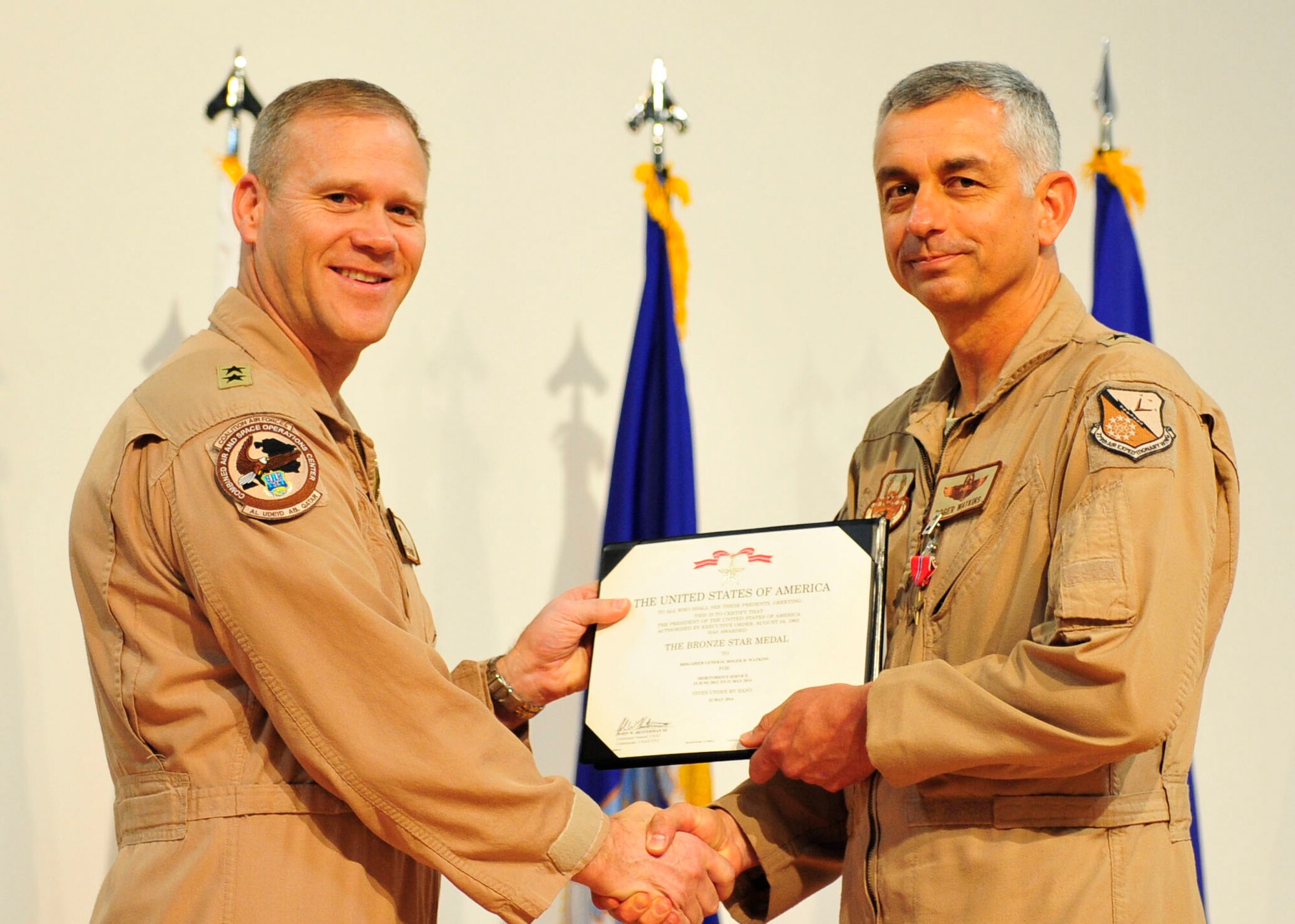 U.S. Air Force Maj. Gen. Jeffrey Lofgren, U.S. Air Forces Central Command deputy commander, presents the Bronze Star to Brig. Gen. Roger Watkins, 379th Air Expeditionary Wing outgoing commander during the change of command ceremony at Al Udeid Air Base, Qatar, June 12, 2014. Watkins will move on the Joint Warfare Center, Supreme Allied Command for Transformation as the deputy commander and chief of staff in Stavanger, Norway. (U.S. Air Force photo by Senior Airman Colin Cates)  