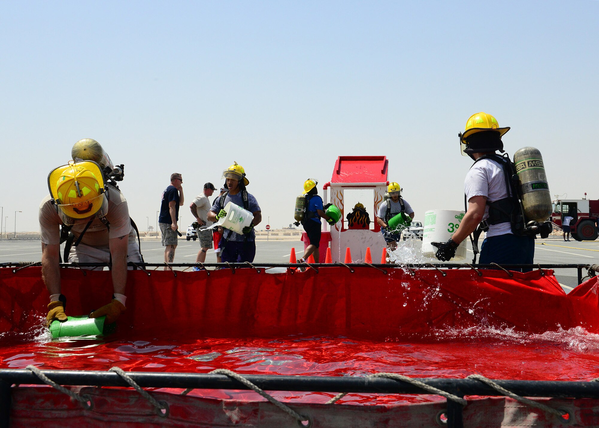 A team races to put out a simulated “burning “ house during a fire muster challenge at Al Udeid Air Base, Qatar, June 7, 2014. The challenge was held to increase camaraderie and team-building skills among the members assigned to AUAB. (U.S. Air Force photo by Staff Sgt. Ciara Wymbs) 