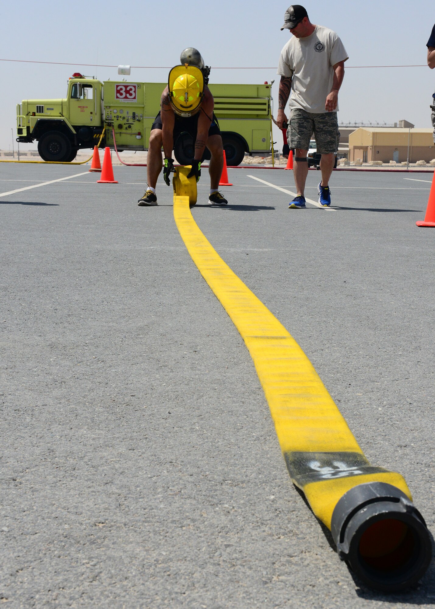 A Service member completes the fire hose throw and roll challenge during a fire muster competition at Al Udeid Air Base, Qatar, June 7, 2014. Participants were timed while completing some of the skills firefighters perform on a regular basis. (U.S. Air Force photo by Staff Sgt. Ciara Wymbs)