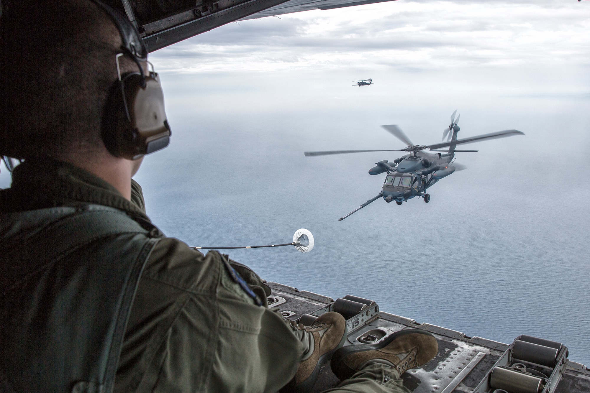 A loadmaster from the 353rd Special Operations Group observe two Japan Air Self-Defense Force UH-60J Black Hawk helicopters June 5, 2014 above the Sea of Japan, during Helicopter Air-to-Air Refueling training. This is the first time that members of the 353rd SOG held HAAR training with Japan Air Self-Defense Force members on Honshu Island in Japan. (U.S. Air Force photo by Osakabe Yasuo/Released)