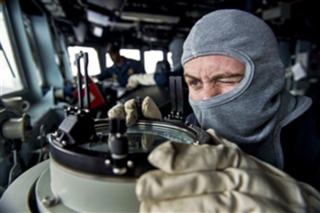 Ensign Sean Lawlor takes a bearing from the bridge during a general quarters drill on the USS Kidd in the U.S. 7th Fleet area of responsibility, June 13, 2014. The Kidd is supporting regional security and stability in the Indo-Asia Pacific region.