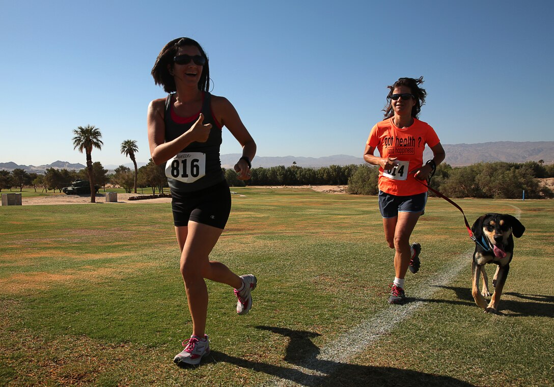 Rachel Abelson, wife of Capt. Pete Abelson, runs alongside Vera Savage, wife of Maj. Glenn D. Savage, and her dog, Pax, during the annual Remembrance Run hosted at Desert Winds Golf Course and Felix Field, May 29, 2014