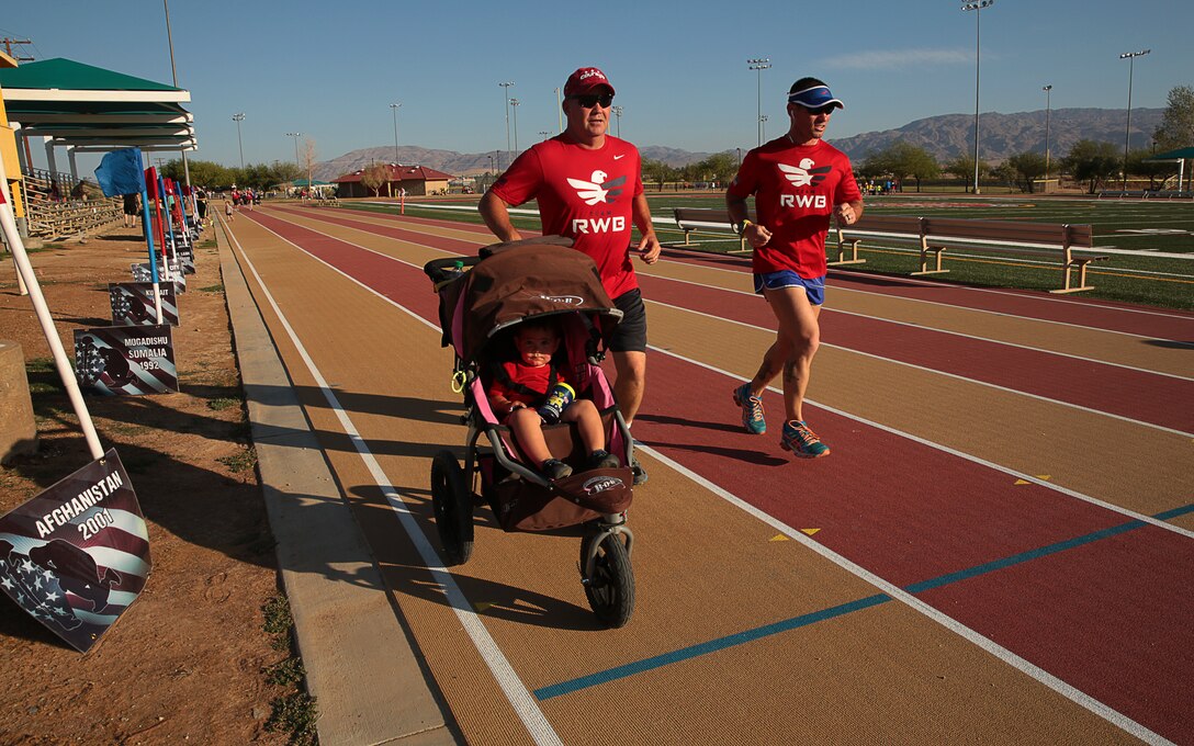 Joshua Stevens, police officer, Provost Marshal’s Office, runs alongside Master Sgt. John Johnson, chief investigator, and his son, Ashton Johnson, 1, during the five-kilometer race of the annual Remembrance Run hosted at Felix Field, May 29, 2014

