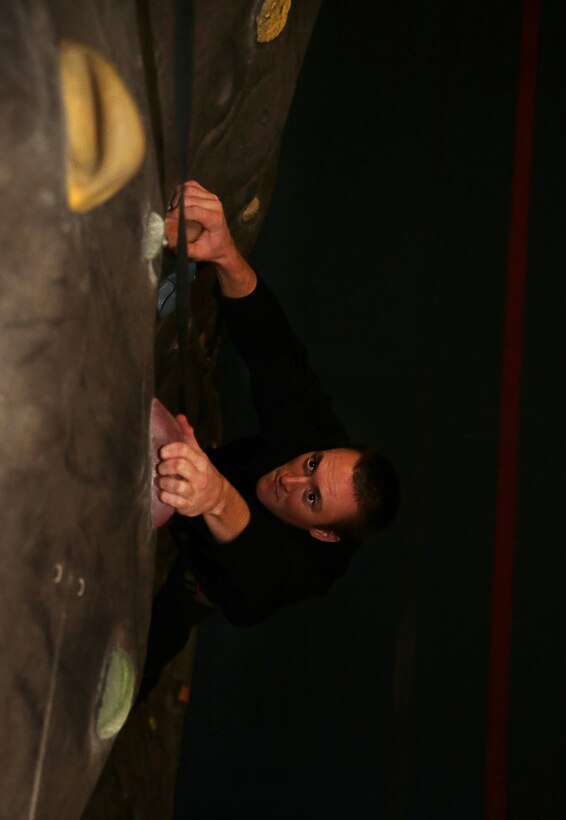 Aric Pope, recreational attendant, West Gym, searches for his next opportunity to advance up the rock-climbing wall at the West Gym, June 4, 2014. With air-conditioning, hydration readily available and safety systems in place, the rock-climbing wall at the West Gym offers a safe facility for all Combat Center patrons.

