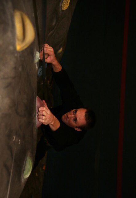 Aric Pope, recreational attendant, West Gym, searches for his next opportunity to advance up the rock-climbing wall at the West Gym, June 4, 2014. With air-conditioning, hydration readily available and safety systems in place, the rock-climbing wall at the West Gym offers a safe facility for all Combat Center patrons.