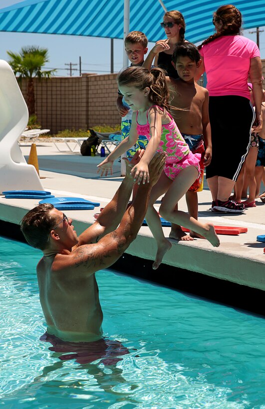 Cpl. Decil Burns, lifeguard and safety swimmer, Training Tank, helps a participant over come her fear of jumping into the pool by catching her on the way down during a swimming class for children hosted at the Training Tank, June 10, 2014. The group of children are part of a program which takes kids who are in home schooling and have them participate in activities that change monthly.

