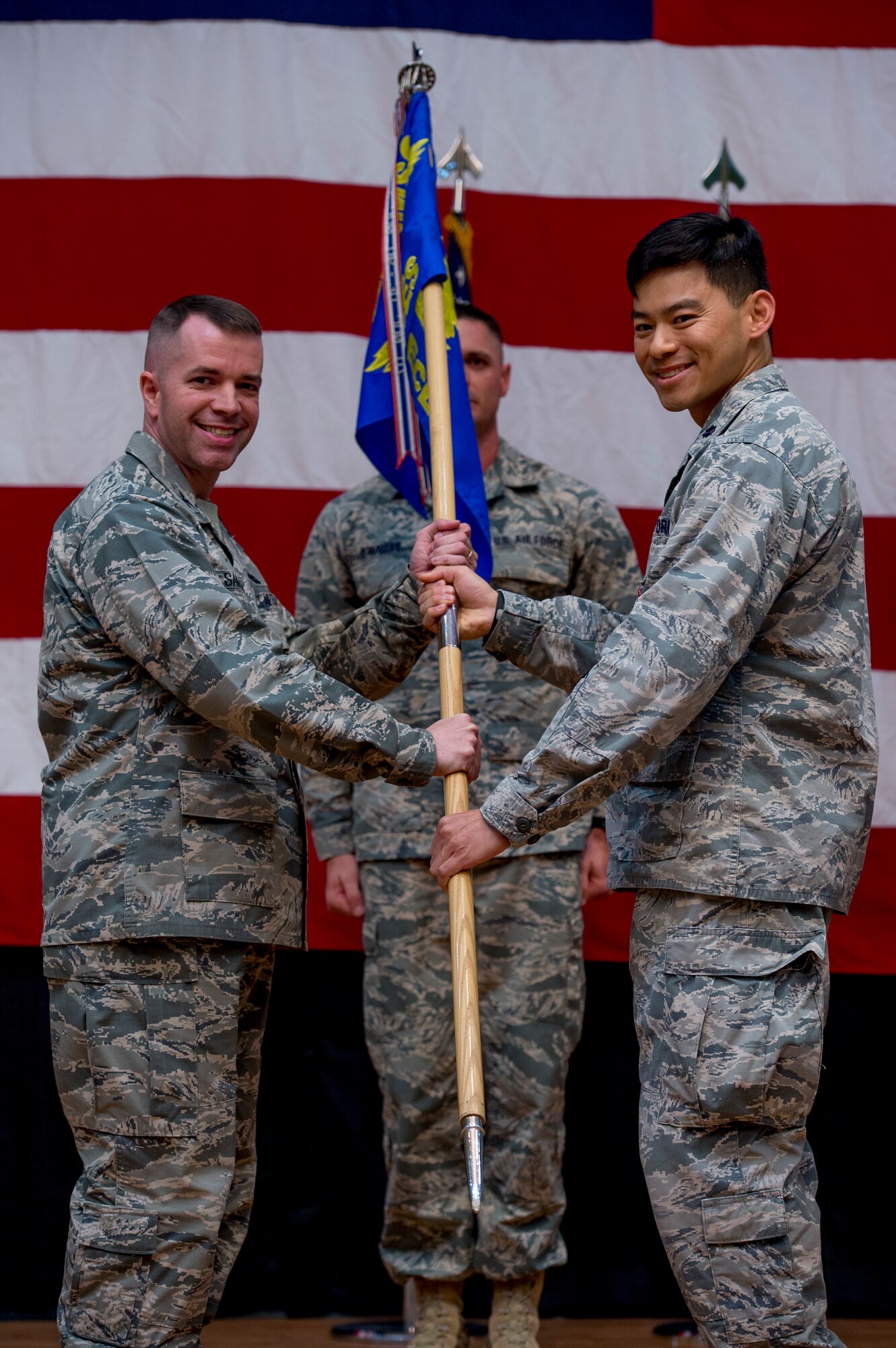 U.S. Air Force Lt. Col Chen Y. Su, 386th Expeditionary Civil Engineer Squadron commander, passes the 386th ECES guidon to Col. David Sanford, 386th Expeditionary Mission Support Group commander, during a change of command ceremony June 11, 2014 at the Rock Theater at an undisclosed location in Southwest Asia. Su will be moving on to Shaw Air Force Base, South Carolina where he will be assigned to U.S. Air Forces Central, installation mission support, deputy director of installations. (U.S. Air Force photo by Staff Sgt. Jeremy Bowcock)