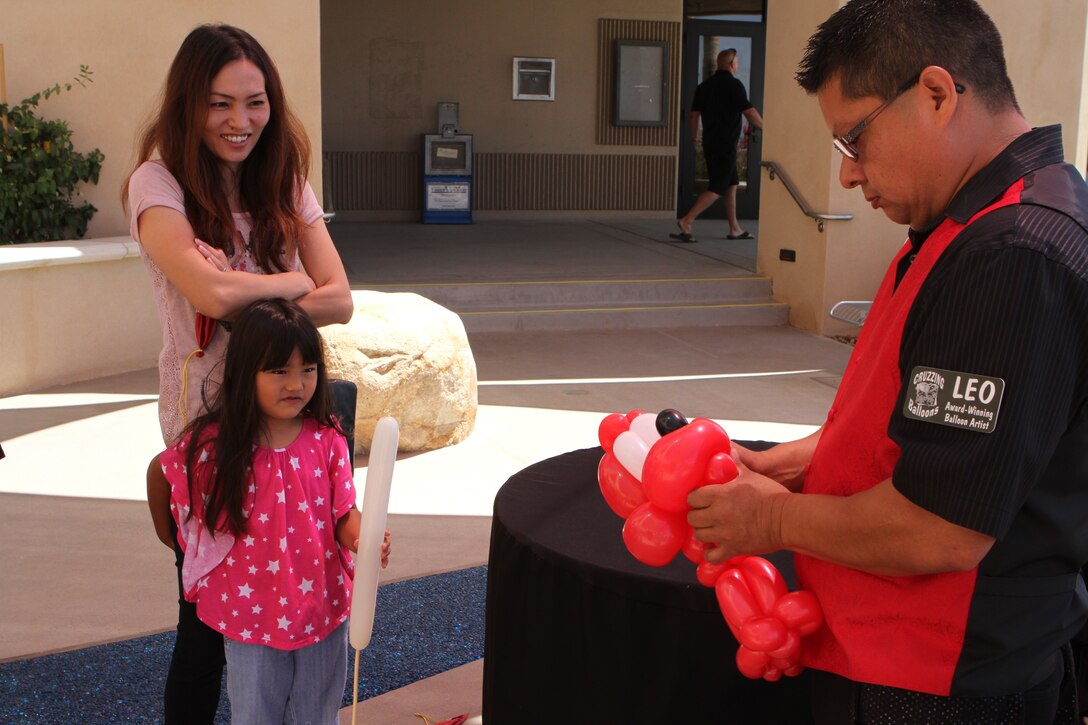 Chamile Cepeda, 5, waits with her mother, Alice Cepeda, for a balloon animal during the grand opening of the food court aboard Marine Corps Air Station Miramar, Calif., June 16. The event marked the official opening of Wendy’s, Panda Express and Subway, and featured raffles, food giveaways, two bounce houses, a rock climbing wall, a balloon artist and a prize wheel. 