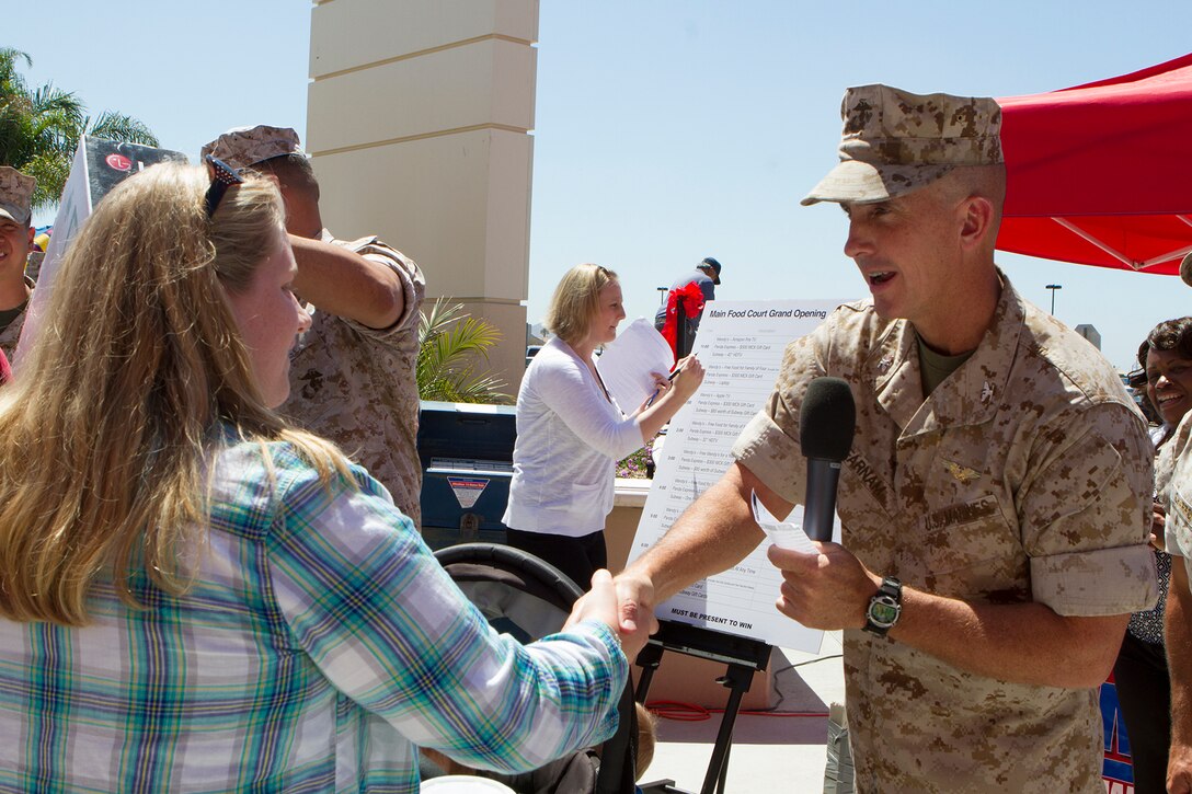 Col. John Farnam, Marine Corps Air Station Miramar commanding officer, congratulates Brittany Workman, military spouse, upon winning a 42-inch high-definition TV during the grand opening of the food court aboard MCAS Miramar, Calif., June 16. The event marked the official opening of Wendy’s, Panda Express and Subway, and features raffles, food giveaways, two bounce houses, a rock climbing wall, a balloon artist and a prize wheel. 