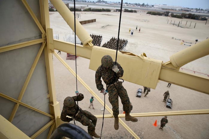 Recruits of Lima Company, 3rd Recruit Training Battalion, fast rope down the "hell hole" of the rappel tower aboard Marine Corps Recruit Depot San Diego, June 6.  Marines with static rope suspension training monitored the exercise from the top and bottom of the tower.