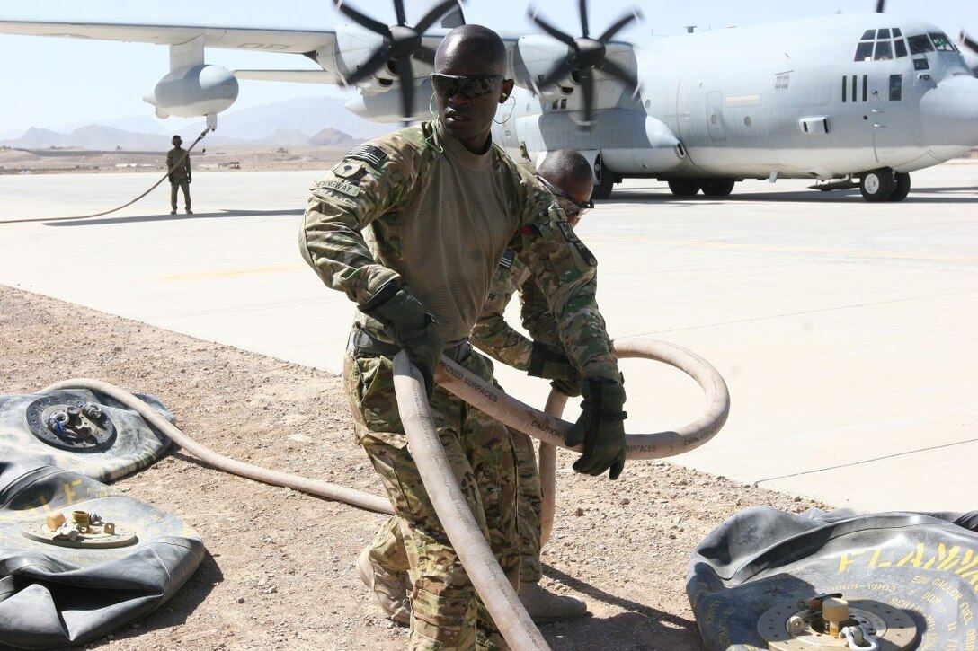 Specialist David Hemmingway, a soldier with 16th Combat Aviation Brigade, Regional Command (South), carries a fuel hose during a refueling operation aboard Multi-National Base Command Tarin Kot, Afghanistan, June 8, 2014. During the operation, Marines with Marine Aerial Refueler Transport Squadron 352, Regional Command (Southwest), provided needed fuel to MNBC Tarin Kot for their future operations. (U.S. Marine Corps photo by Cpl. Cody Haas/ Released)