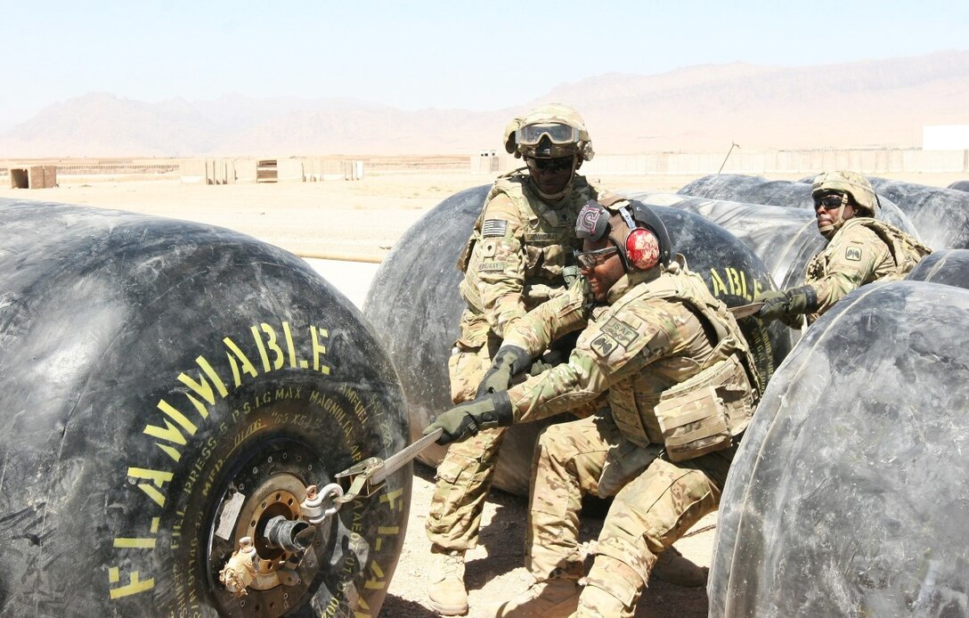 Soldiers with 16th Combat Aviation Brigade, Regional Command (South), reposition a fuel bladder aboard Multi-National Base Command Tarin Kot, Afghanistan, June 8, 2014. A total of 13 fuel bladders were filled and positioned in a row in approximately one hour. During the operation, Marines with Marine Aerial Refueler Transport Squadron 352, Regional Command (Southwest), provided needed fuel to MNBC Tarin Kot for their future operations. (U.S. Marine Corps photo by Cpl. Cody Haas/ Released)