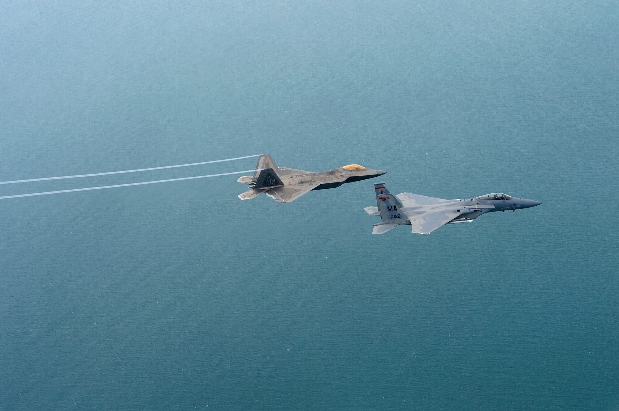 A U.S. Air Force F-22 Raptor from the 154th Wing, Joint Base Pearl Harbor-Hickam, Hawaii, and U.S. Air Force F-15 Eagle from the 131st Fighter Squadron, 104th Fighter Wing, Barnes Air National Guard Base, Mass., fly over Penang, Malaysia, during Cope Taufan 14, June 16, 2014. Cope Taufan is a biennial large force employment exercise taking place June 9 to 20 designed to improve U.S. and Malaysian combined readiness. (U.S. Air Force photo by Tech. Sgt. Jason Robertson/Released)