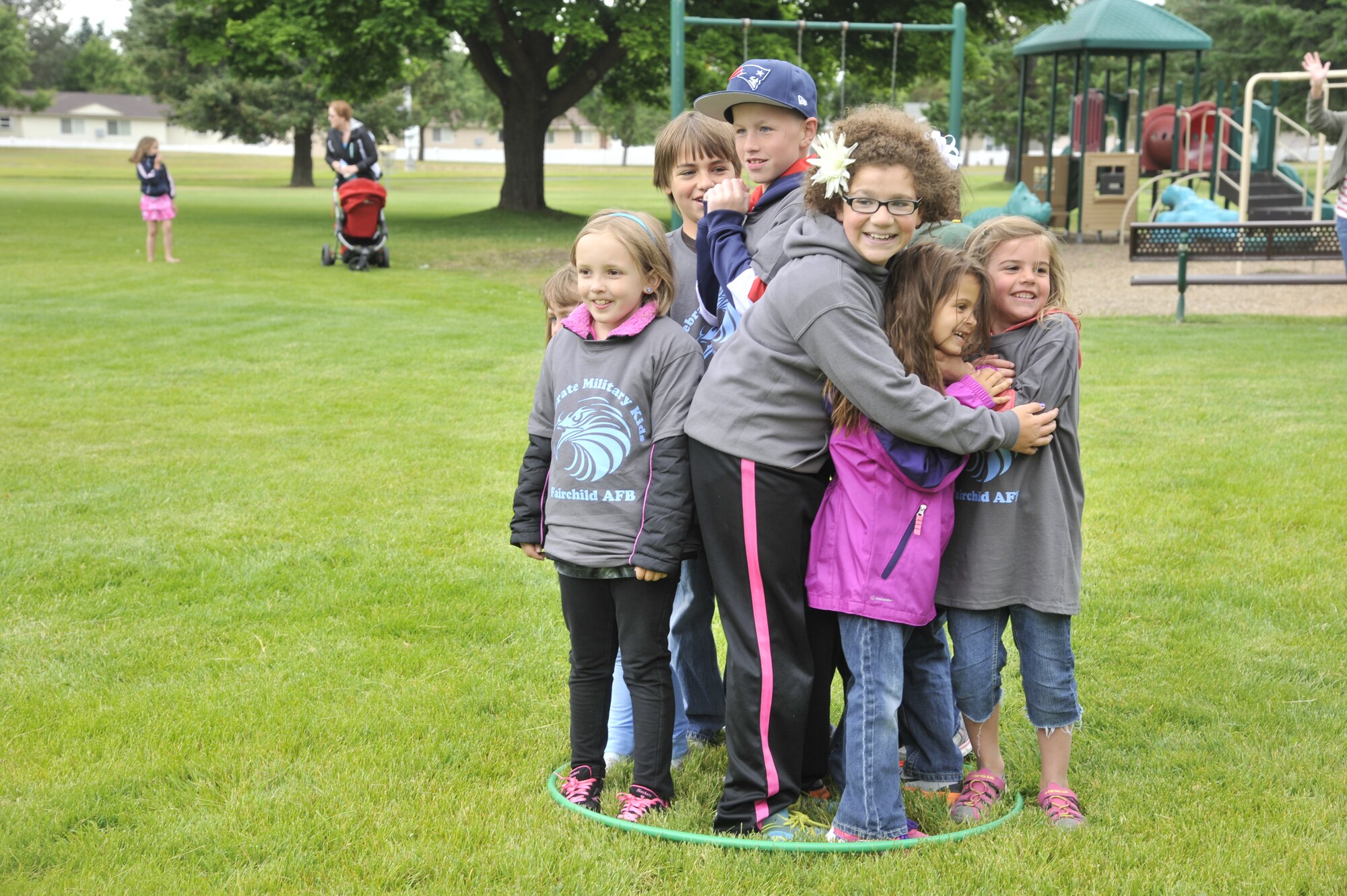 A group of children huddle together inside a hula-hoop during "musical hoops," a game similar to musical chairs, during an event at Fairchild Air Force Base, Wash., June 14, 2014. This event, Celebrate Military Children, was held by a local physical education teacher in honor of her father, an Army veteran, who recently passed away and to share his love for being physically active. (U.S. Air Force photo by Senior Airman Mary O'Dell/Released)