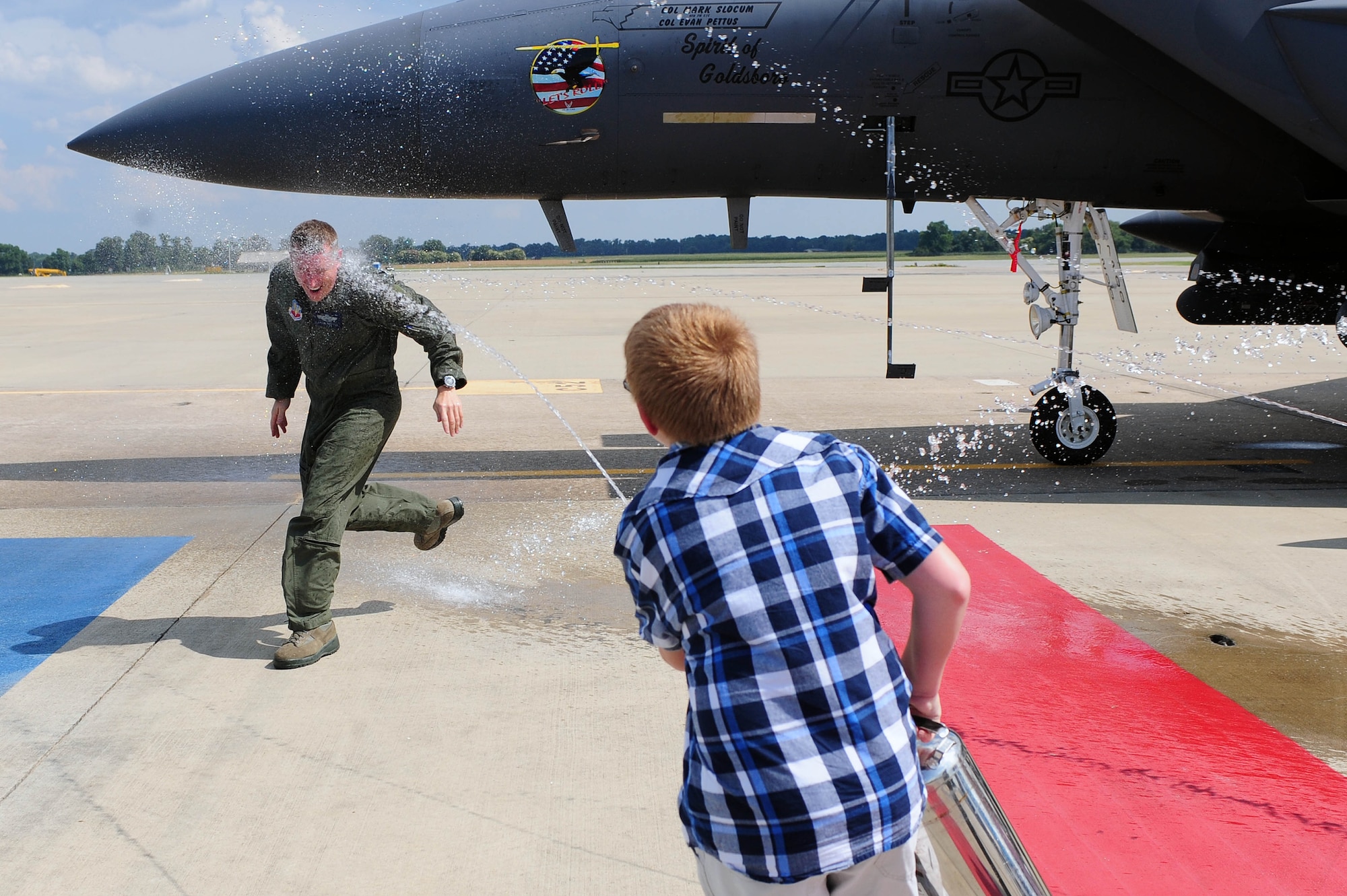 Col. Lamar Pettus, 4th Fighter Wing vice commander, is hosed down by his child after his fini-flight, June 13, 2014, at Seymour Johnson Air Force Base, North Carolina. A fini-flight is a military aviation tradition that marks the end of a pilot’s or commander’s time at a location or command. (U.S. Air Force photo/Senior Airman John Nieves Camacho)