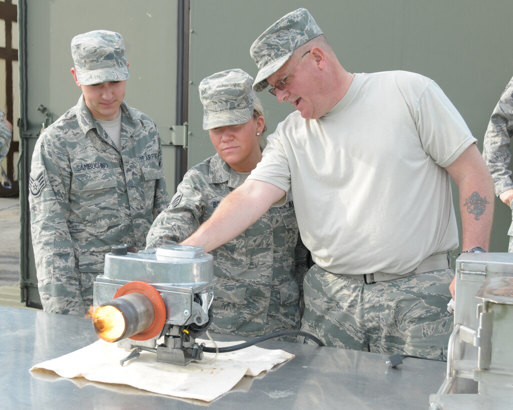 Master Sergeant  Andrew Smith (Right),readiness non-commissioned officer in-charge, 914th Force Support Squadron demonstrates how the Babington Burner works to Staff Sergeant Christopher Sambuchino (left), lodging specialist and Senior Airman Courtney Booker, food services specialist also of the 914th Force Support Squadron at the Niagara Falls Air Reserve Station, N.Y. on June 9, 2014. The burner is used to keep food hot when food service workers are serving troops meals under field conditions. (U.S. Air Force photo by Peter Borys)