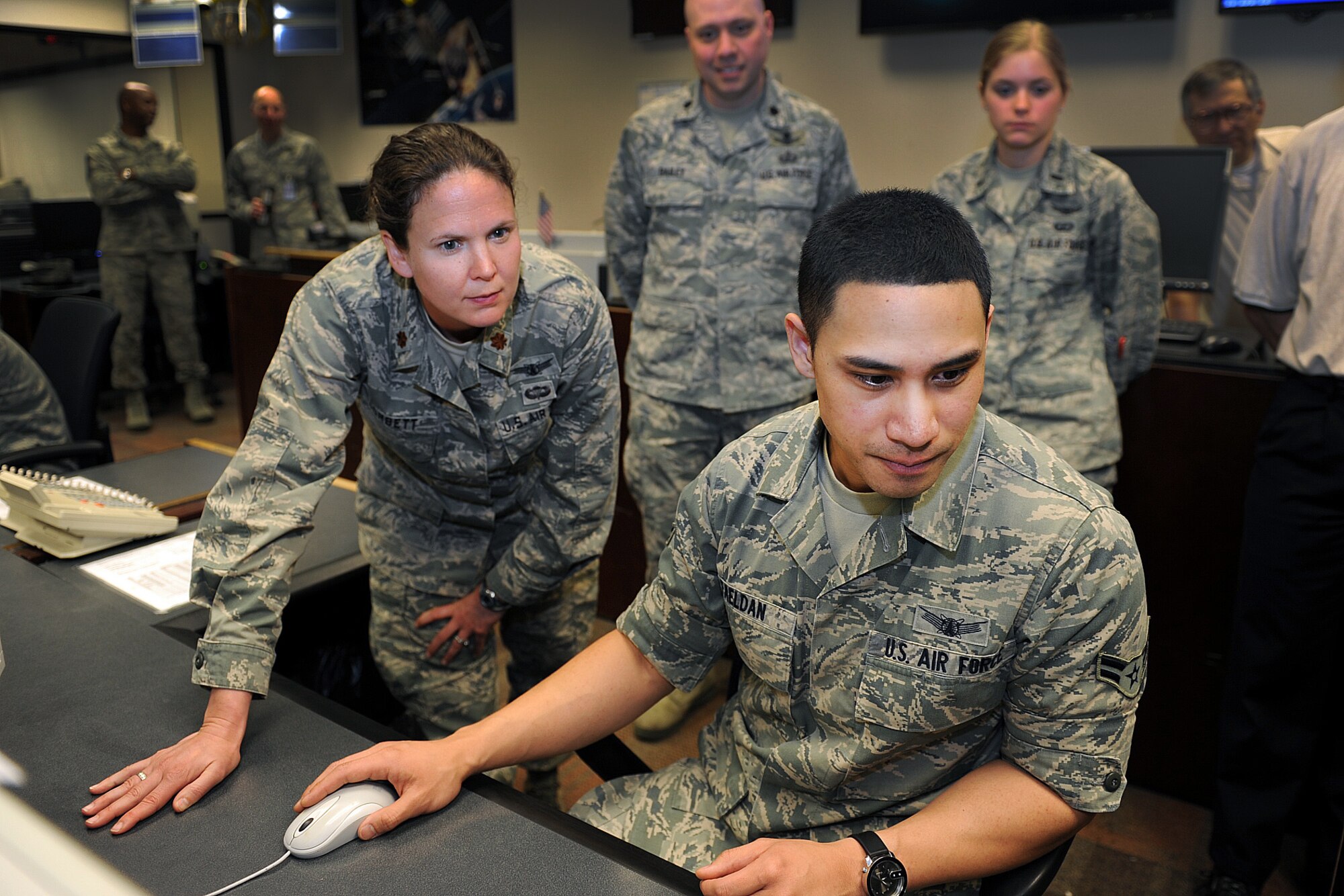 Maj. Shanna Corbet, 19th Space Operations Squadron, reviews procedures with Airman 1st Class Alan Faeldan, 2nd Space Operations Squadron, during the Civil Navigation implementation April 28, 2014, at Schriever Air Force Base, Colo. The initiative will allow Air Force Space Command to broadcast Civil Navigation messages on all operational GPS satellites capable of transmitting L2C and L5 signals. 