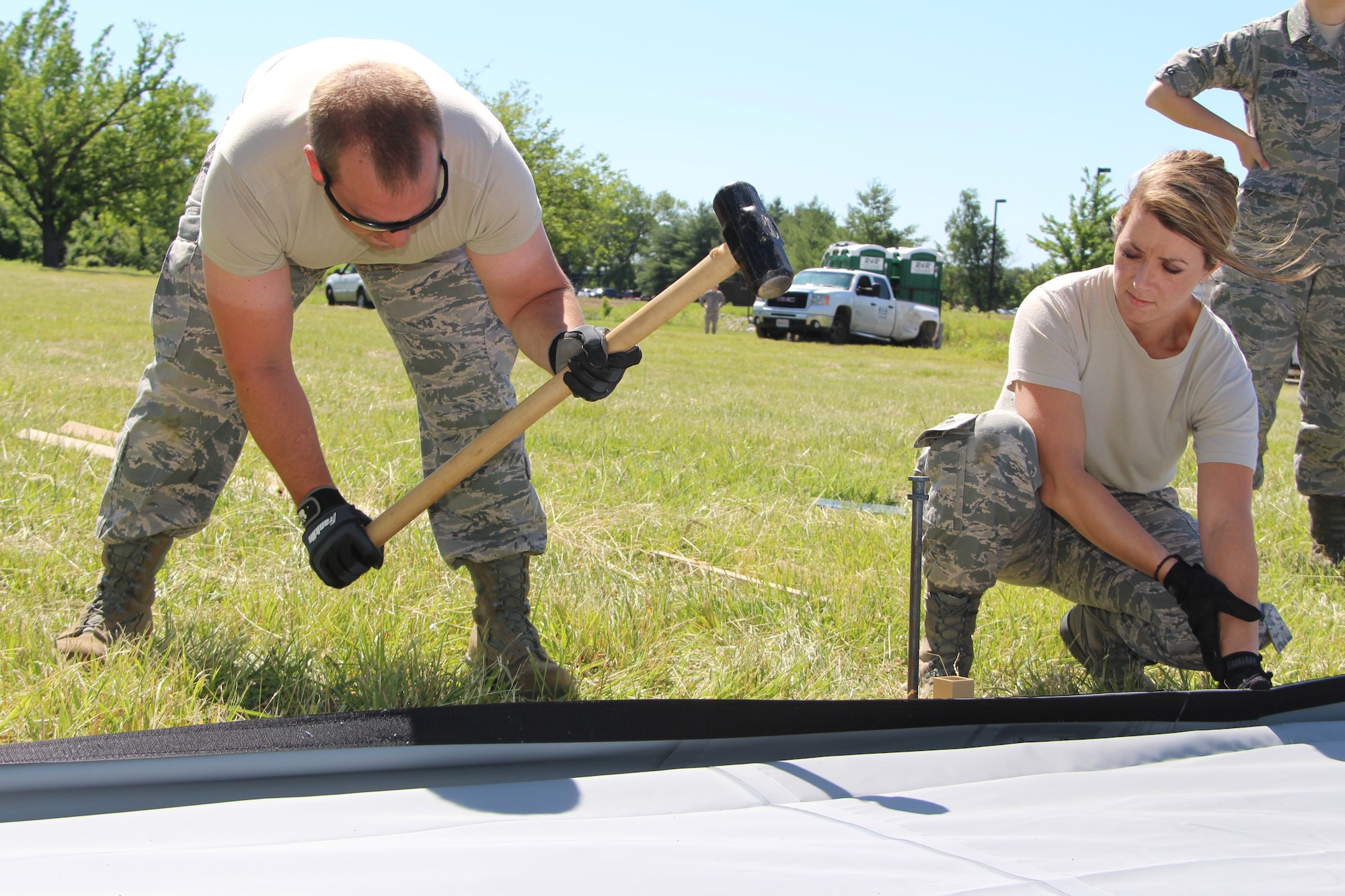 Staff Sgt. Brenton Darnell of 932nd Airlift Wing Medical group hammers down a stake for an Alaskan tent floor as Staff Sgt. Kristi Dimarco looks on.  Member of the 932nd AW Medical Group worked for several hours to get the tent up and ready to go in preparation for a training exercise this month. (U.S. Air Force Photo/Staff. Sgt. Meiko Schill)