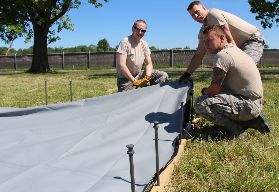 From left, Staff Sgt. John Wood, Capt. Todd Dean and Senior Airman Daniel Paregien, members of 932nd Airlift Wing Medical group wait to stake down floor for an Alaskan tent.  Member of the 932nd AW Medical Group worked for several hours to get the tent up and ready to go in preparation for a training exercise this month. (U.S. Air Force Photo/Staff. Sgt. Meiko Schill)