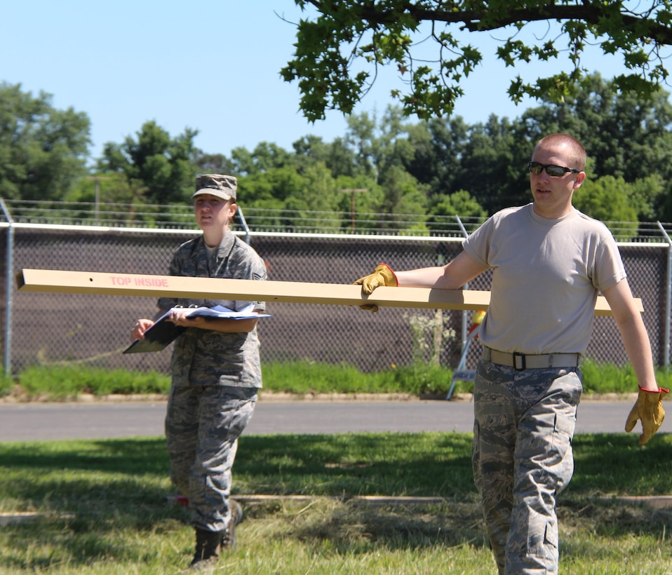 Staff Sgt. John Wood of the 932nd Airlift Wing Medical Group carries a metal beam that will be used to create a Alaskan tent as Senior Airman Christina Griffin looks on.  Member of the 932nd AW Medical Group worked for several hours to get the tent up and ready to go in preparation for a training exercise this month. (U.S. Air Force Photo/Staff. Sgt. Meiko Schill)
