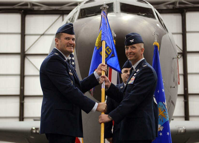 U.S. Air Force Col. Kenneth T. Bibb Jr., left, 100th Air Refueling Wing commander, passes the guidon to U.S. Air Force Col. Noel Bradford, incoming 100th Operations Group commander, during the 100th OG change of command ceremony June 16, 2014, on RAF Mildenhall, England. U.S. Air Force Col. Nancy Bozzer relinquished command to Bradford. (U.S. Air Force photo/Airman 1st Class Dillon Johnston/Released)