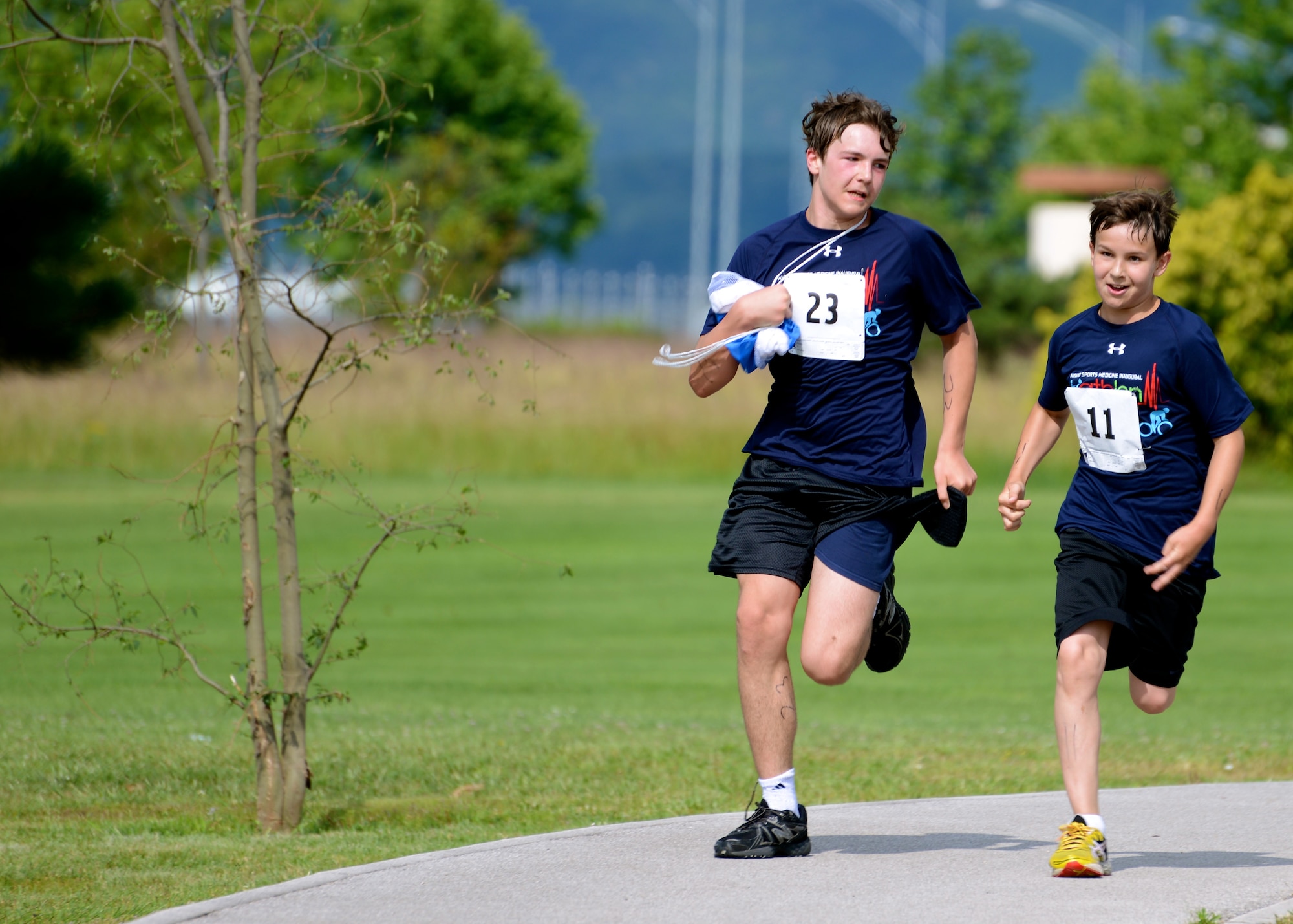Luke and Mitchell Farrington, triathlon competitors, race to the finish line during the Aviano Sports Medicine Triathlon, June 14, 2014, at Aviano Air Base, Italy. Luke and Mitchell tied for third place in the male under-18-year-old bracket with a time of 1:39:57. During the competition, participants swam 500 meters, biked 16 kilometers and ran a 5k. More than 30 individuals competed, ranging in age from 9 to 53 years old. (U.S. Air Force photo/Capt. Lacie Collins)