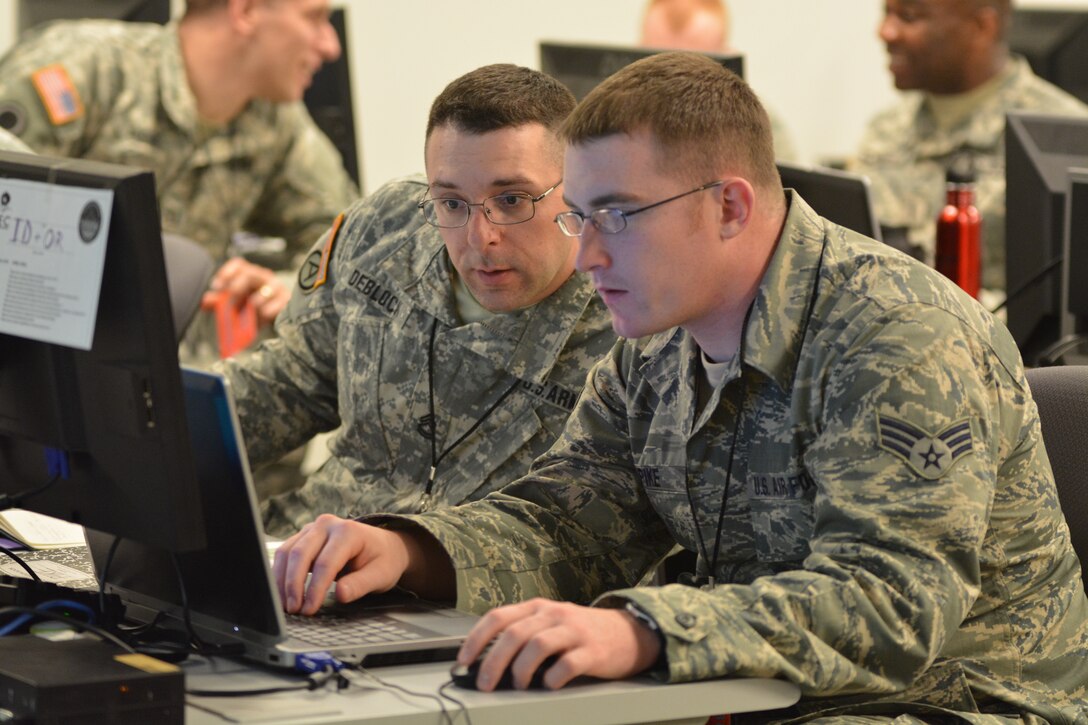 Army Sgt. 1st Class Michael Deblock, Vermont Army National Guard Computer Network Defense Team, left, discusses new ways to make the exercise more challenging for cyber defenders with a fellow Red Cell team member during the 2014 Cyber Shield exercise at the National Guard Professional Education Center, North Little Rock, Ark., April 29, 2014. U.S. Army photo by Staff Sgt. Kelvin Green