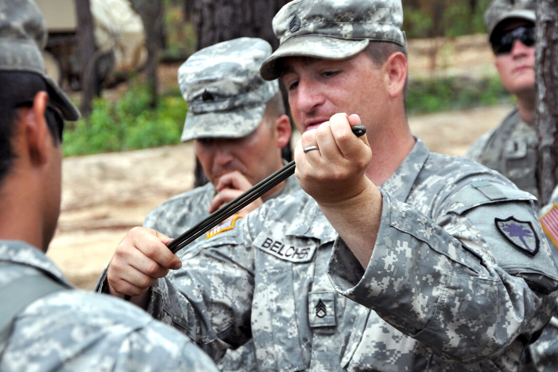 Army Staff Sgt. John Belcher, center, instructs soldiers how to prepare