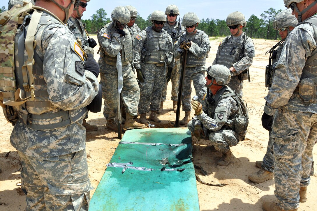 Army Staff Sgt. David Teel, kneeling, examines his soldiers’ water impulse charge after detonation during a demolition range exercise at McCrady Training Center in Eastover, S.C., June 6, 2014. Teel, a combat engineer, is assigned to the South Carolina National Guard's 222nd Engineer Company.