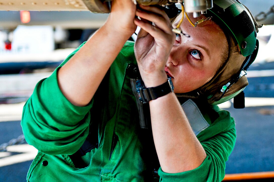 U.S. Navy Seaman Christina McCallum replaces a cannon plug on an MH-60R Sea Hawk helicopter aboard the aircraft carrier USS John C. Stennis in the Arabian Sea, Oct. 18, 2011. McCallum is an aviation electronics technician airman.  
