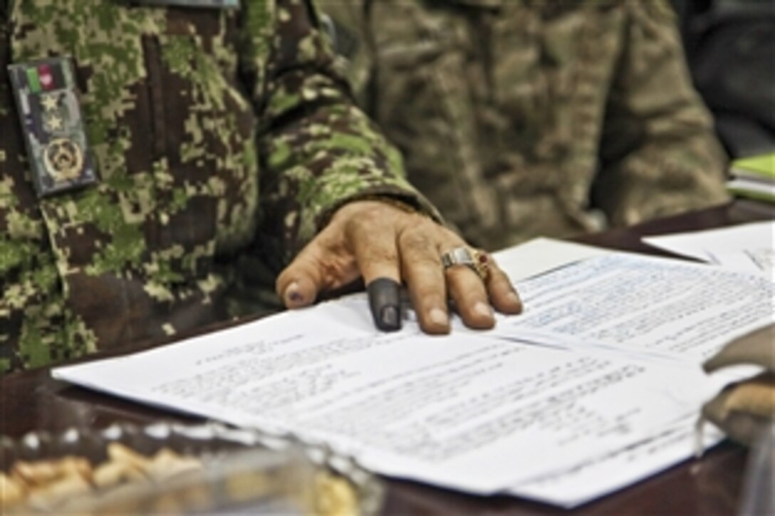 An Afghan security forces member with ink on his finger sits next to a U.S. member of the International Security Assistance Force as they await results for presidential runoff elections and plan counterinsurgency tactics on Forward Operating Base Gamberi in Afghanistan's Laghman province, June 14, 2014. Black ink on an index finger indicates an Afghan citizen has voted.