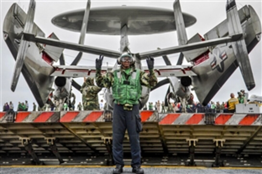 U.S. Navy Seaman Donovan Dunn signals to raise a jet blast deflector  during carrier qualifications on the aircraft carrier USS Ronald Reagan in the Pacific Ocean, June 14, 2014. Dunn is an aviation boatswain’s mate airman.