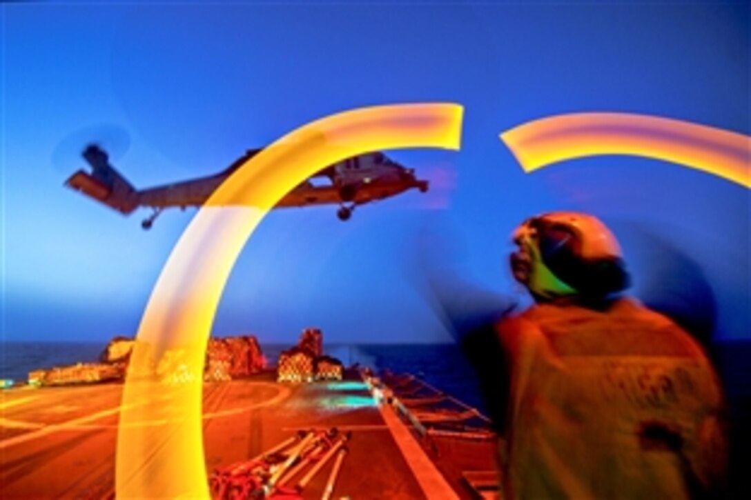 U.S. Navy seaman Clayton Jackson guides an MH-60S Sea Hawk helicopter assigned to Sea Combat Squadron 28 during a night vertical replenishment aboard the guided-missile cruiser USS Philippine Sea in the Arabian Sea, June 11, 2014. Jackson is a boatswain's mate. The Philippine Sea is deployed as part of the George H.W. Bush Carrier Strike Group supporting maritime security operations and theater security cooperation efforts in the U.S. 5th Fleet area of responsibility.