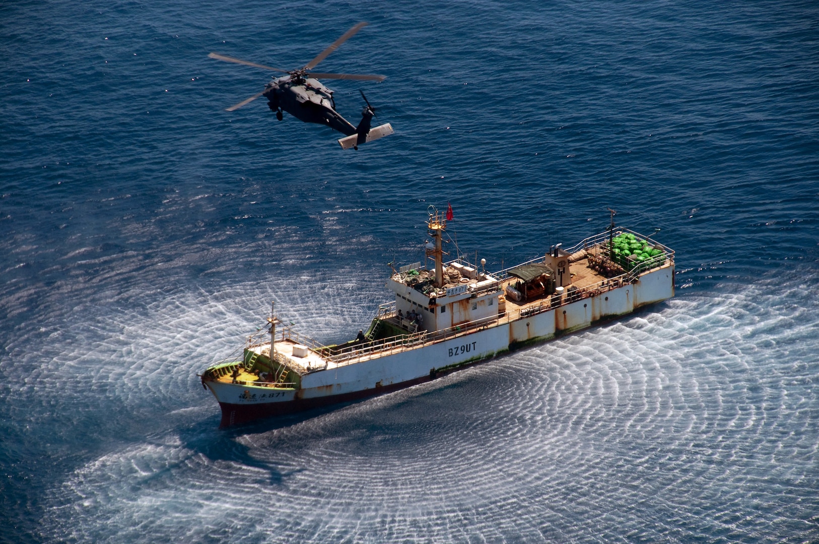 An HH-60G Pave Hawk rescue helicopter from the California Air National Guard's 129th Rescue Wing hovers over a Chinese fishing vessel, the Fu Yuan Yu #871, March 12, 2012. Guardian Angel pararescuemen from the 129th rescued two fishermen who were severely burned during an onboard diesel fire approximately 700 miles off the coast of Acapulco, Mexico.