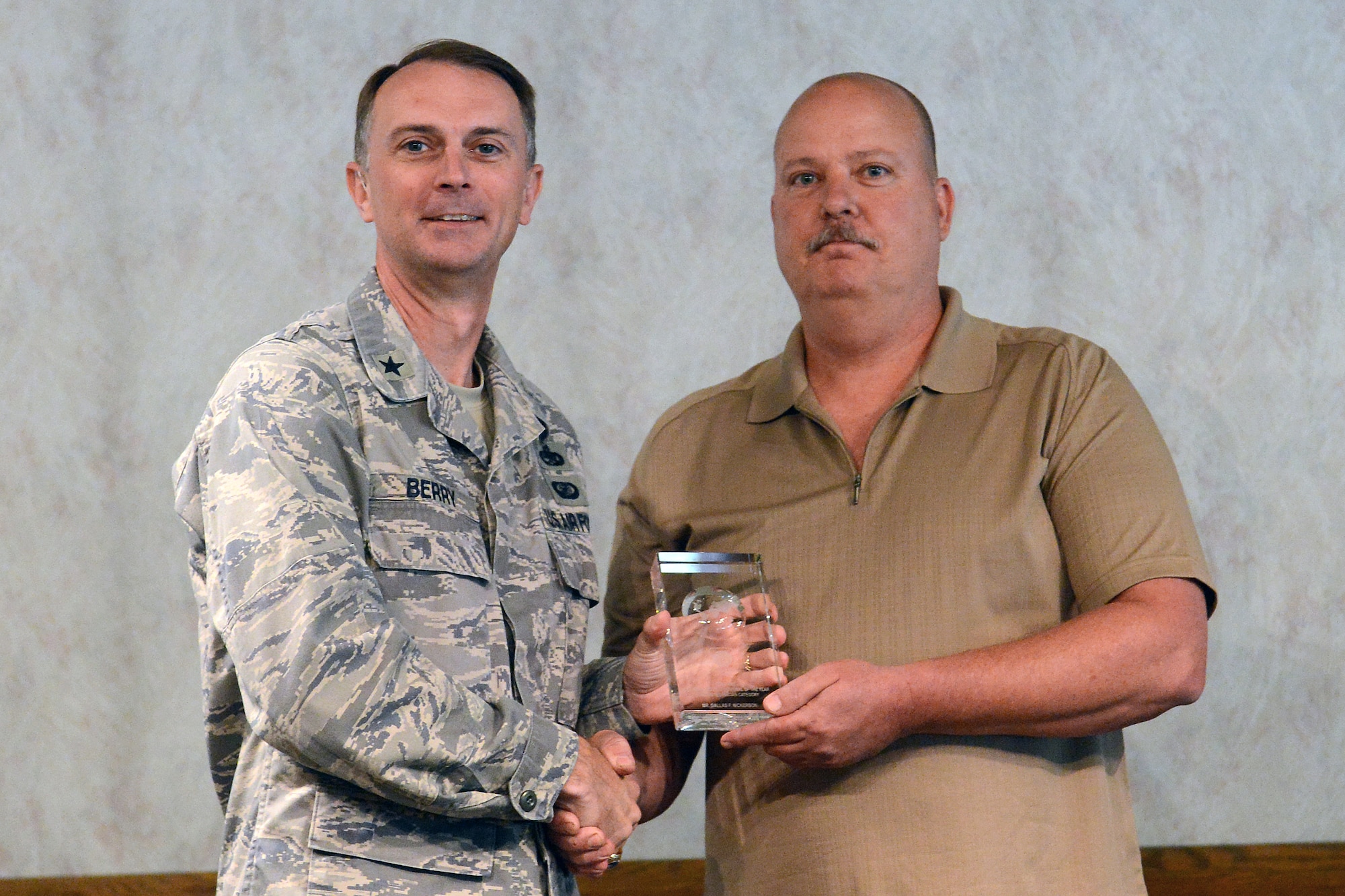 Brig. Gen. Warren Berry (left), Headquarters Air Mobility Command director of logistics, presents Dallas Nickerson, 62nd Maintenance Squadron aerospace ground equipment technician, with the AMC Maintenance Professional of the Year award June 12, 2014, at Joint Base Lewis-McChord, Wash. The AMC Maintenance Professional of the Year award is given to top performers in the maintenance field with a record of outstanding work and technical expertise. (U.S. Air Force photo/Senior Airman Rebecca Blossom)