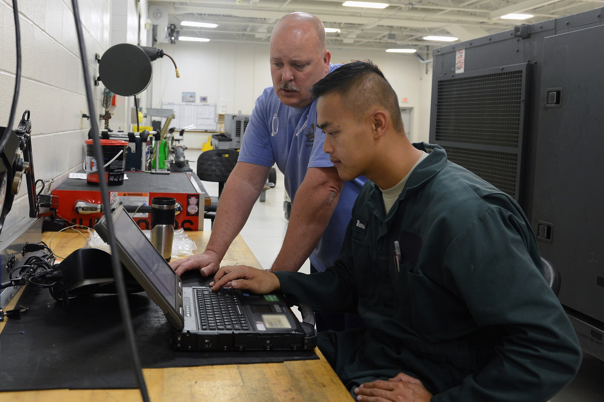 Dallas Nickerson (left), 62nd Maintenance Squadron aerospace ground equipment technician, reviews technical data with Airman 1st Class Jewell Ramos, 62nd MXS AGE technician, June 12, 2014, at Joint Base Lewis-McChord, Wash. Nickerson, who retired after 20 years of Air Force service and continued on as a civilian maintainer, has been an AGE technician for more than 30 years. (U.S. Air Force photo/Senior Airman Rebecca Blossom) 