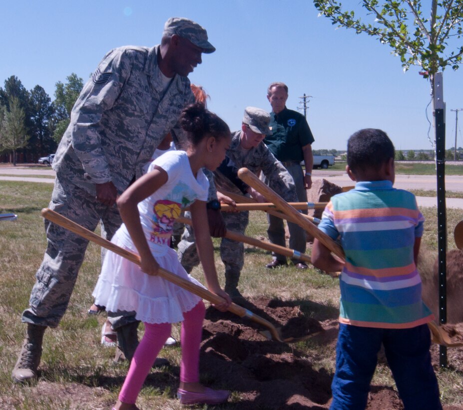 Tech. Sgt. Waleed Jones, 90th Civil Engineer Squadron Heating, Ventilation and Air Conditioning, and his family, take part in a ceremonial breaking of the soil in which a tree was planted to celebrate Arbor Day June 13, 2014, along Randall Avenue near Atlas West housing. (U.S. Air Force photo by Airman 1st Class Jason Wiese)