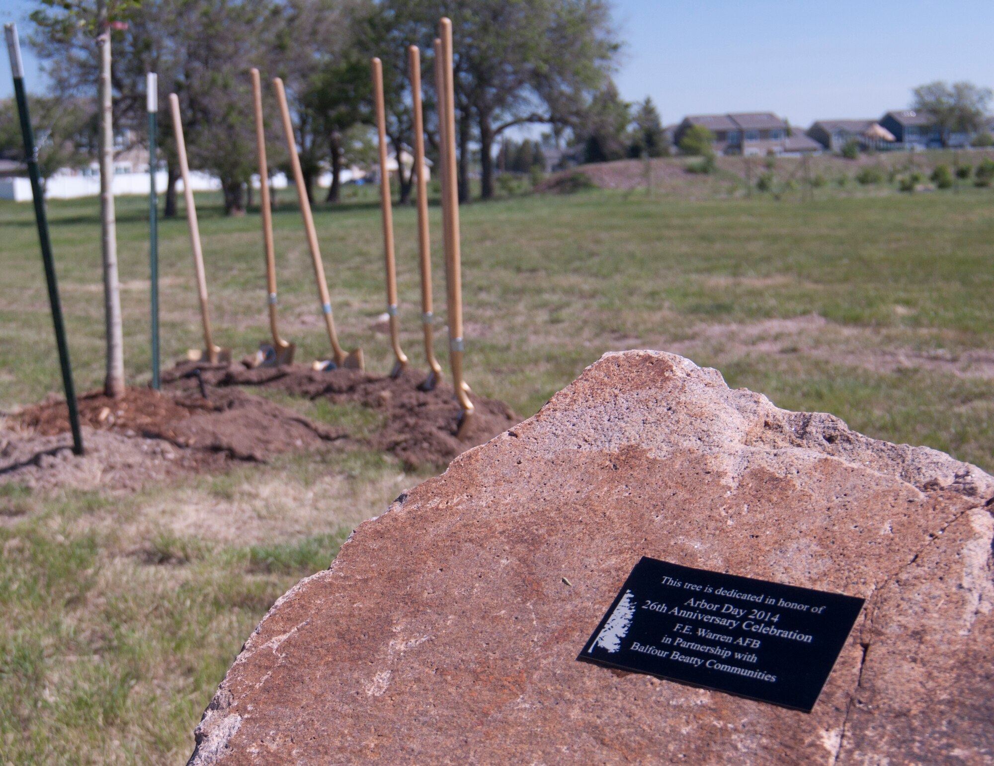 A plaque afixed to a rock near Randall Avenue and Atlas West housing on F.E. Warren Air Force Base, Wyo., reads: "This tree is dedicated in honor of Arbor Day 2014 26th Anniversary Celebration F.E. Warren AFB in Partnership with Balfour Beatty Communities." Ceremonial golden shovels await use to commemorate Arbor Day by breaking the ground where the tree is planted June 13, 2014. (U.S. Air Force photo by Airman 1st Class Jason Wiese)
