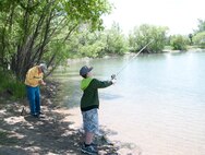 Gunner, grandson of Retired Lt. Col. Jim McHugh, casts a fishing line into the F.E. Warren Base Lake June 15, 2014, during the Father's Day Fishing Derby while his grandfather readies his line to do the same. (U.S. Air Force photo by Airman 1st Class Jason Wiese)