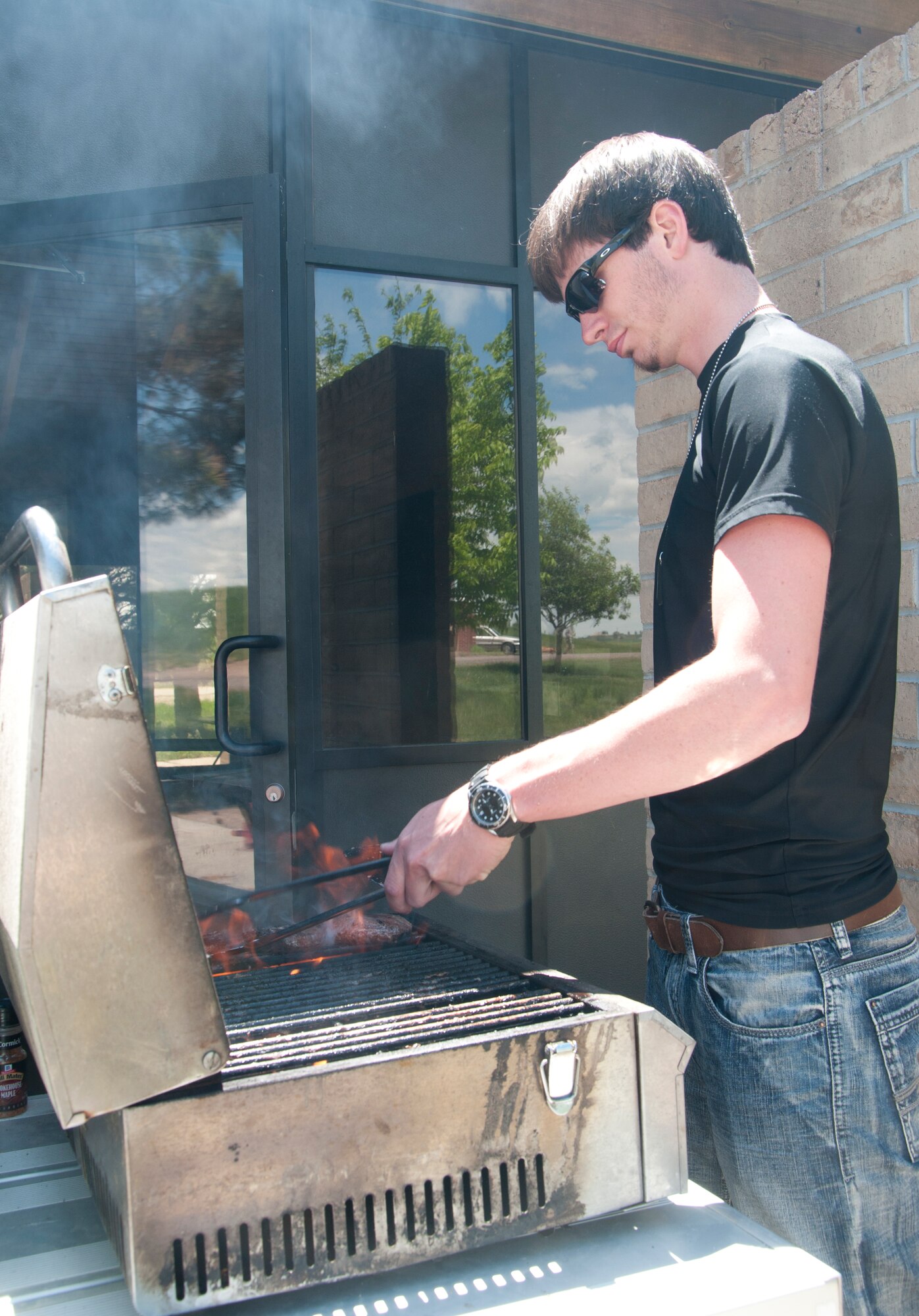 Kyle, son of Gus Schliffke, 90th Force Support Squadron Outdoor Recreation, barbecues hamburgers and hot dogs for people attending Outdoor Rec's Father's Day Fishing Derby June 15, 2014, at the F.E. Warren Base Lake. (U.S. Air Force photo by Airman 1st Class Jason Wiese)