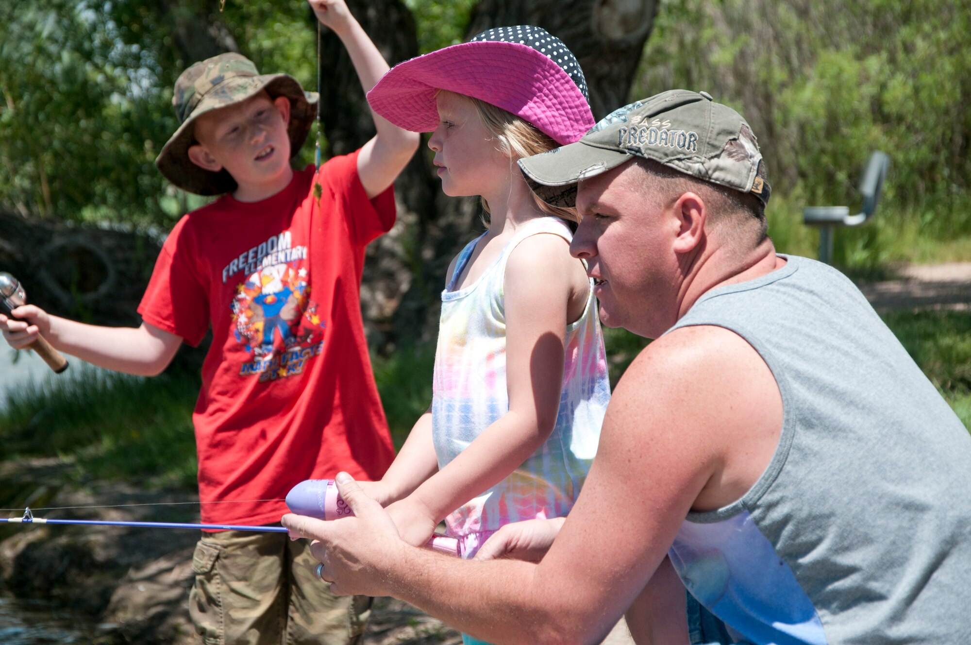 Tech. Sgt. Kevin Adams, 90th Missile Security Forces Squadron, helps his daughter, Grace, cast her reel at the Father's Day Fishing Derby June 15, 2014, at the F.E. Warren Base Lake while his son Wyatt gets his line ready. (U.S. Air Force photo by Airman 1st Class Jason Wiese)
