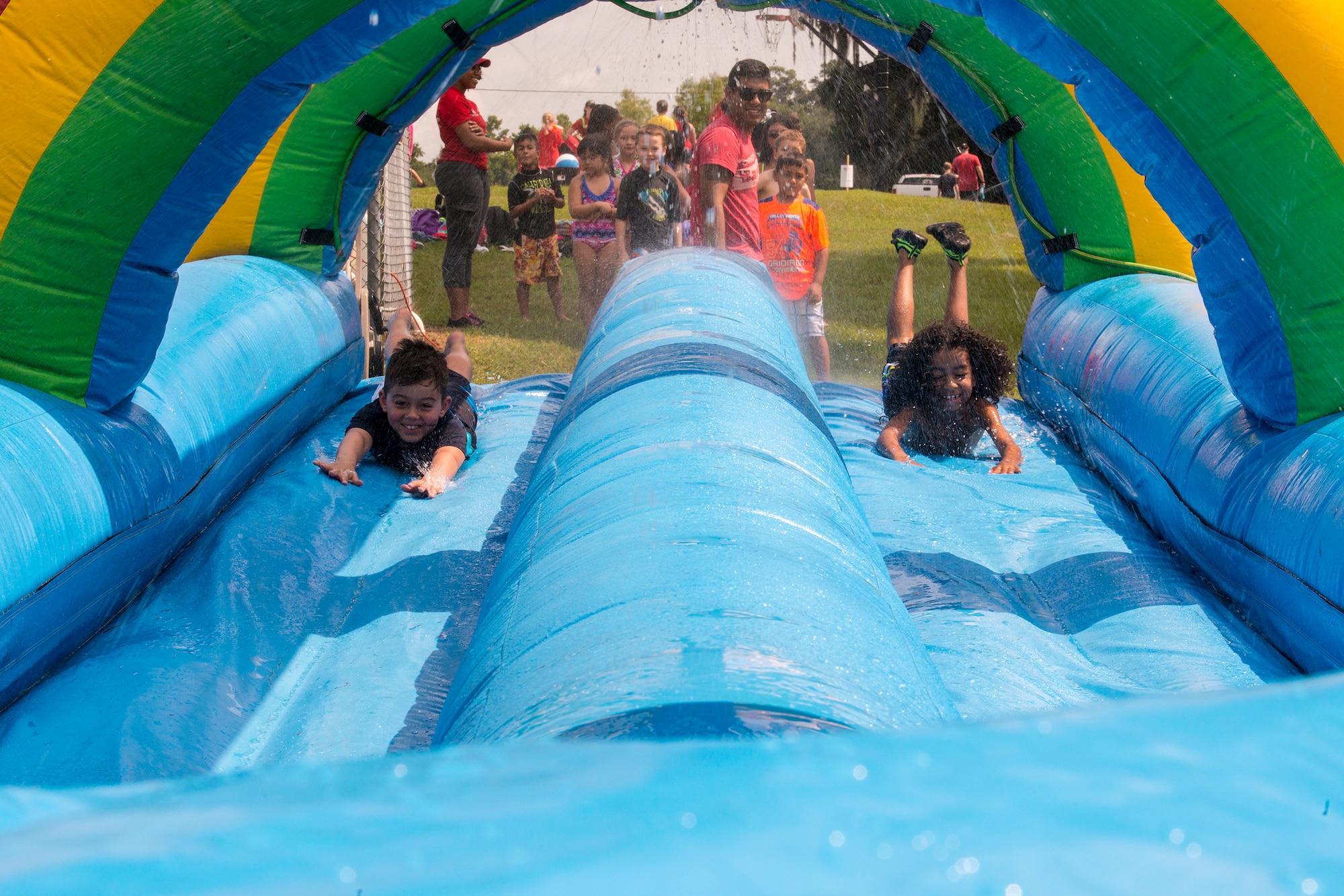 Children from Moody’s Youth Programs and the local community race on a water slide during Moody’s Olympic Day celebration at Grassy Pond in Lake Park, Ga., June 13, 2014. Lewis Gordan, 27-year Special Olympics Georgia athlete, was present at the event as a guest speaker. (U.S. Air Force photo by Airman 1st Class Ryan Callaghan/Released)