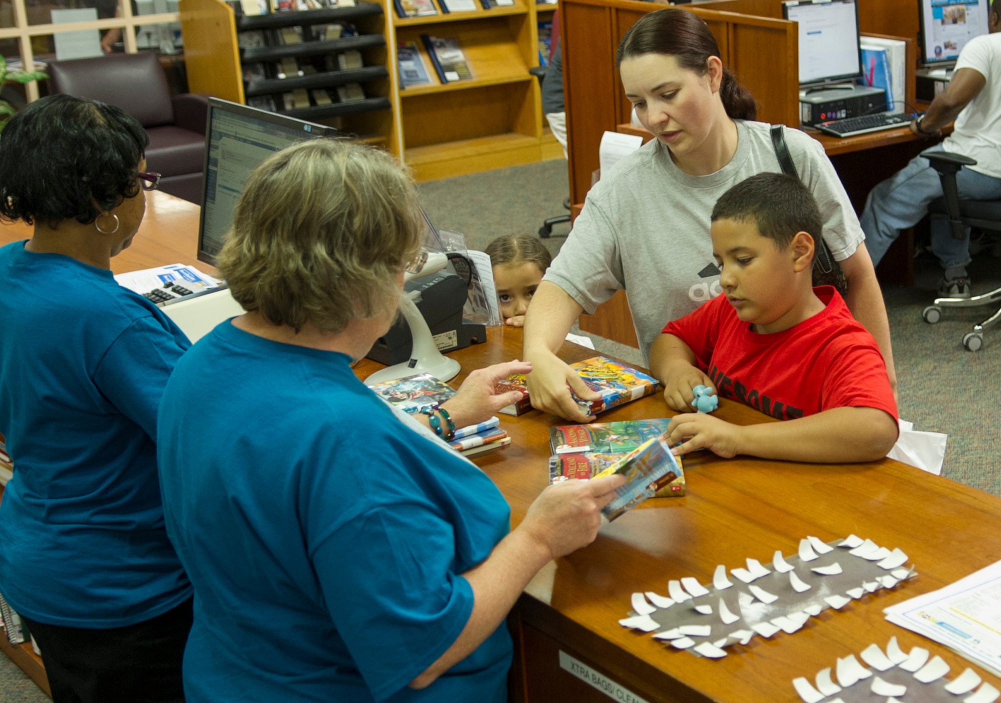 Heather Toro and her children, Olivia and William, check out books at the Andrews Library's 'Paws to Read' summer reading program kickoff party at Joint Base Andrews, Md., June 16, 2014. The program encourages children to read during the summer months and the library is slated to host weekly events for children to attend. (U.S. Air Force photo/Staff Sgt. Torey Griffith)