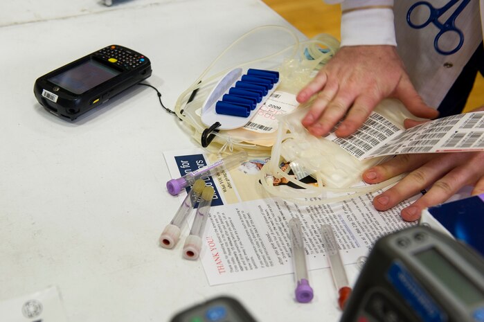 An American Red Cross member prepares materials for blood donation at the Air Base gym, June 12, 2014, at Joint Base Charleston, S.C. Members of JB Charleston had the opportunity to donate with the help of the American Red Cross, which utilizes volunteers to aid those in need during emergency situations. (U.S. Air Force photo/Senior Airman George Goslin)