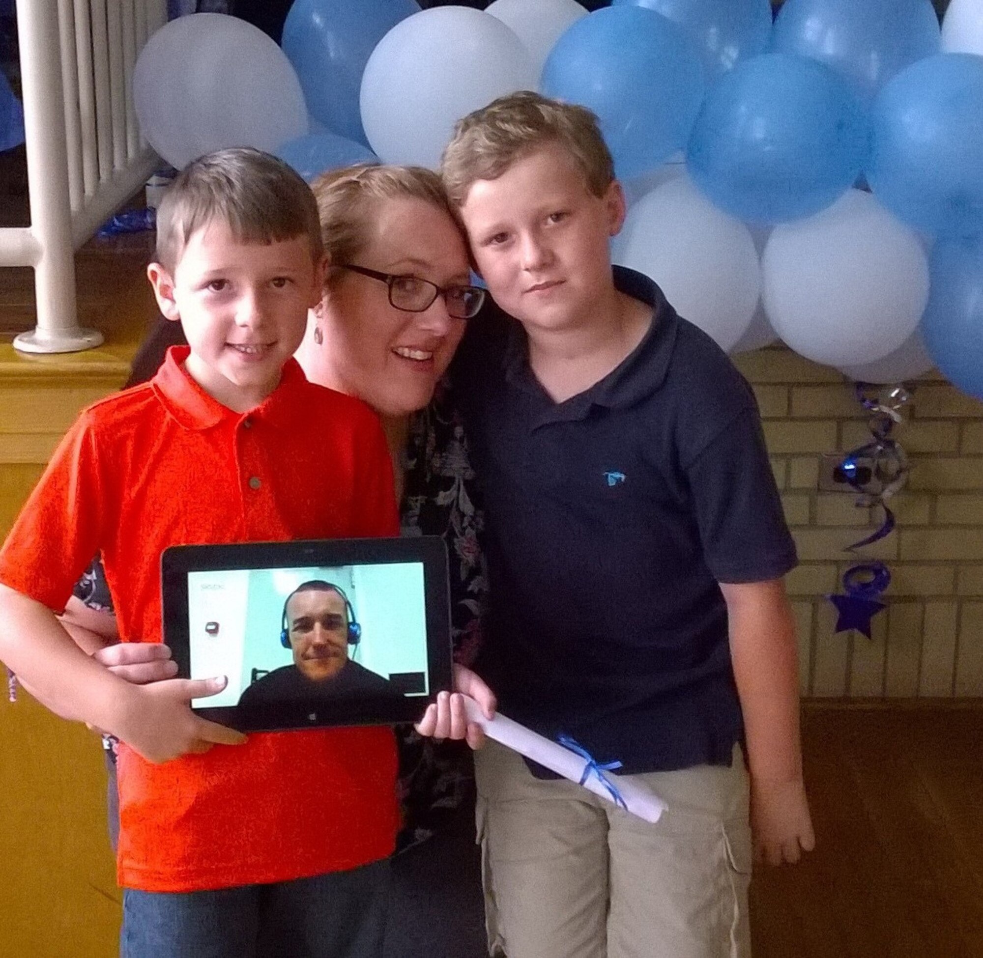 Tech. Sgt. Benjamin Hamilton (on tablet screen), tunes in live to witness the kindergarten graduation of his son Cody (left) at Lake Forest East Elementary June 5, 2014. School officials assisted Hamilton's wife Jessica in arranging the video call for her husband, who's a 512th Maintenance Group reservist currently deployed to Mihail Kogalniceanu Air Base, Romania. Their son Colton also shared the experience with his family. (Submitted photo)
